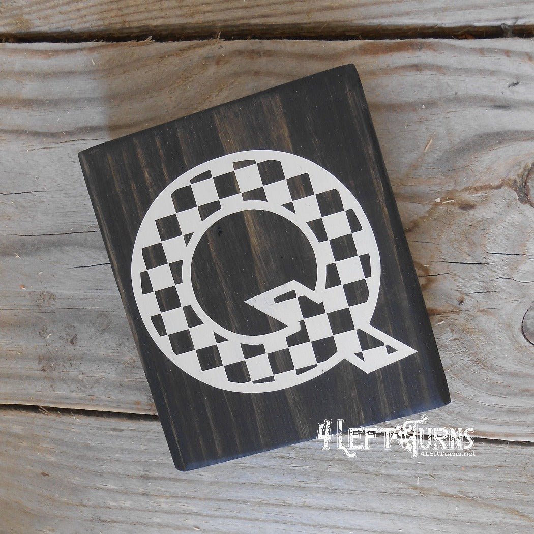 Block of wood with painted on checkered letter Q.