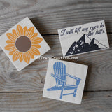 Small signs featuring a sunflower, mountains and an Adirondack chair.