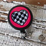 Pink background checkered heart badge reel clip.