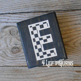 Block of wood with painted on checkered letter E.