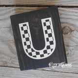 Block of wood with painted on checkered letter U.