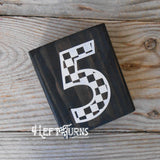Block of wood with painted on checkered number 5.