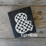 Block of wood with painted on checkered ampersand.