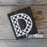 Block of wood with painted on checkered letter D.