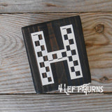 Block of wood with painted on checkered letter H.