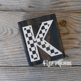 Block of wood with painted on checkered letter K.