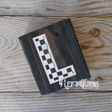 Block of wood with painted on checkered letter L.