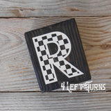 Block of wood with painted on checkered letter R.