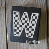 Block of wood with painted on checkered letter W.