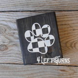 Block of wood with painted on checkered pawprint.